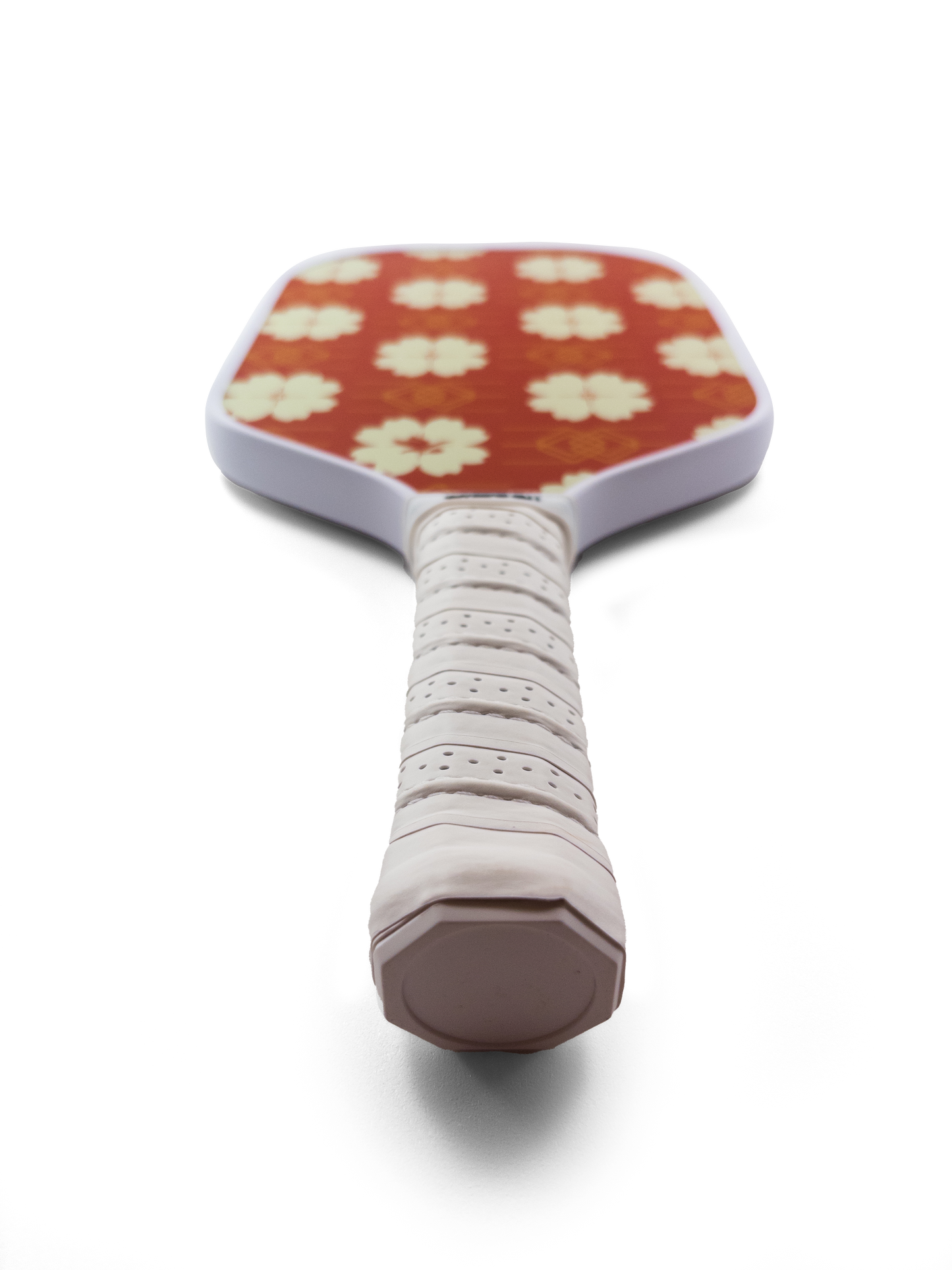 Bottom view of a honeycomb core pickleball paddle with yellow / white floral pattern on a red background.