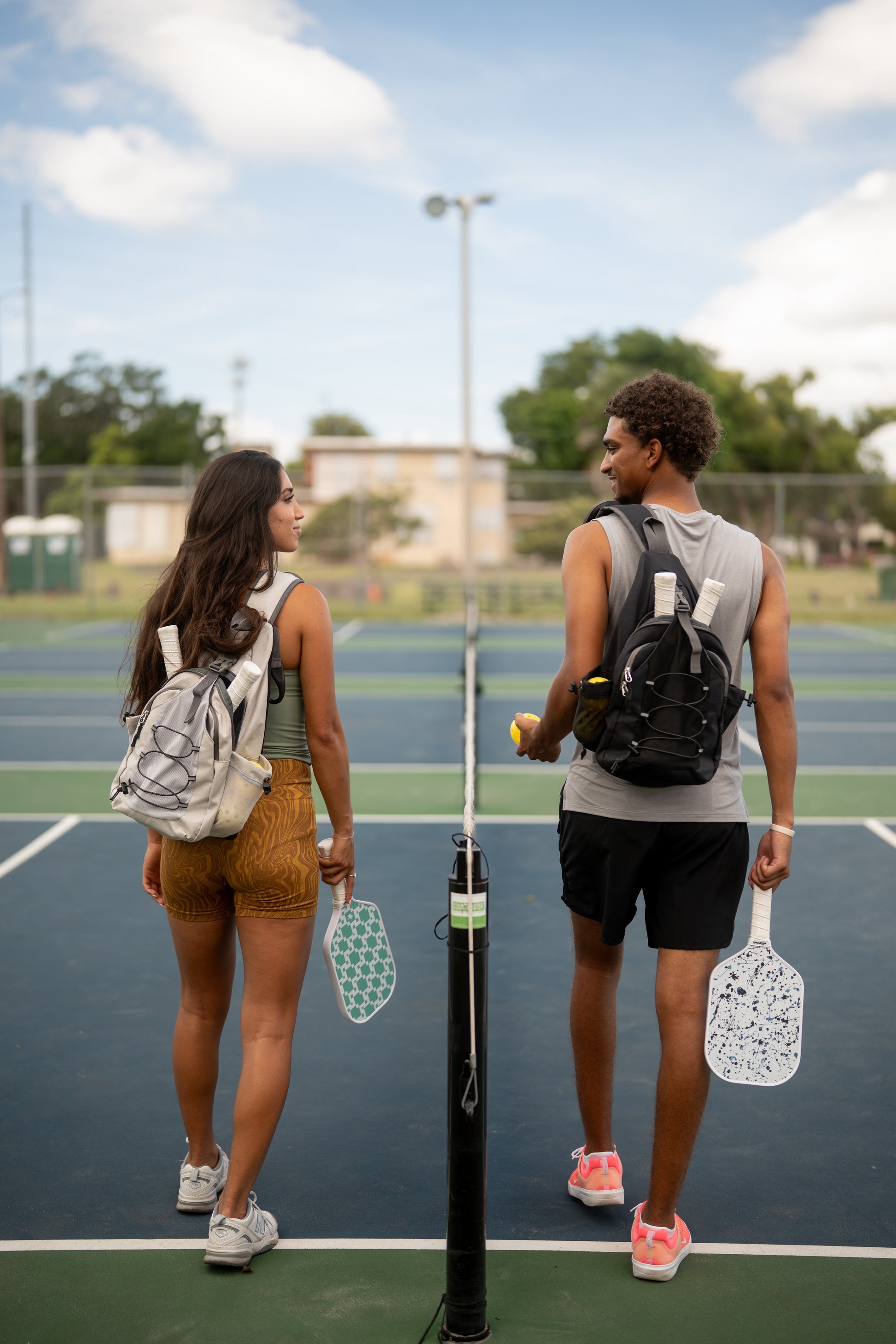 Two people on a pickleball court with paddles and other equipment