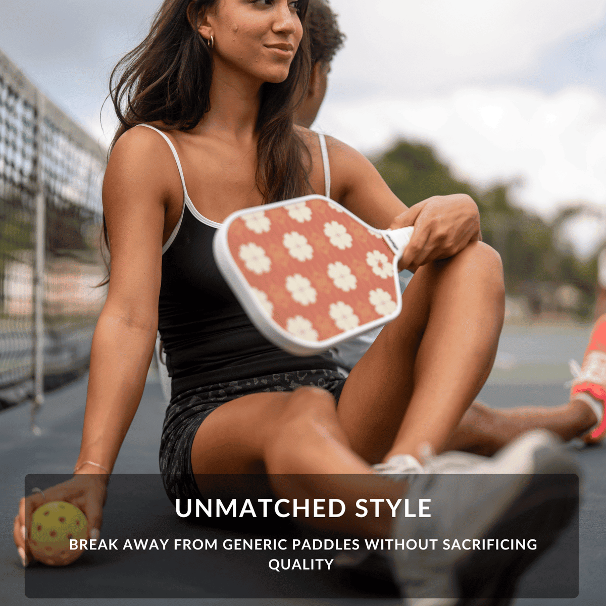 Woman holding a pickleball paddle with a floral design on a court