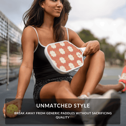 Woman holding a pickleball paddle with a floral design on a court