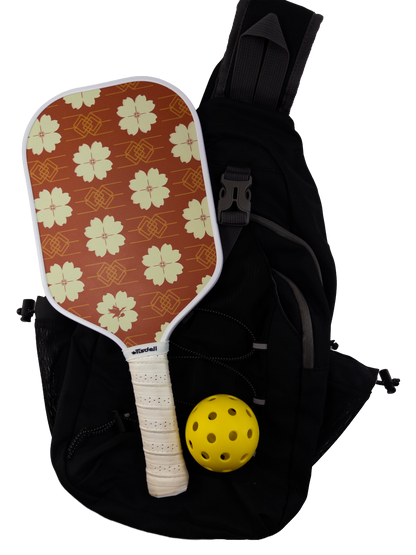 Pickleball paddle with floral design and yellow ball inside a black bag on a white background