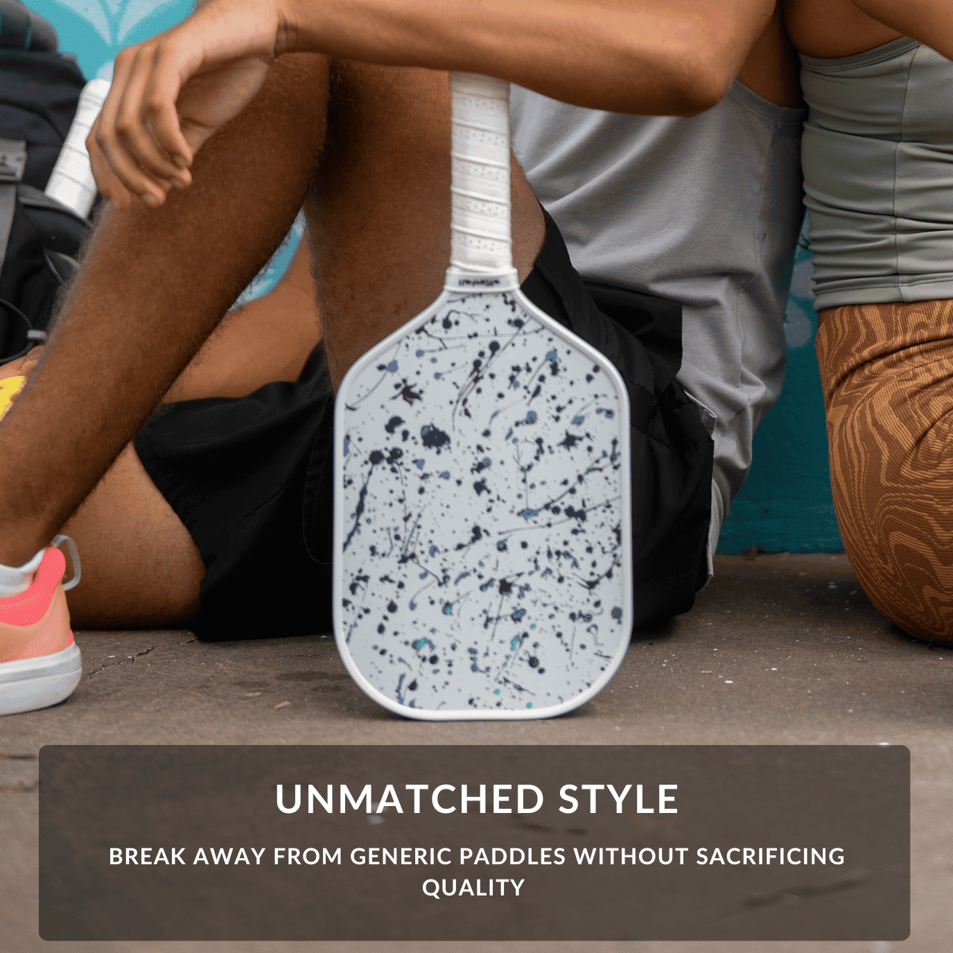 Splattered pickleball paddle held by a person sitting on a court with text about unmatched style