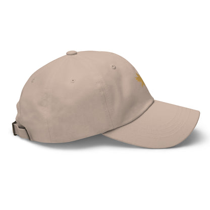 Side view of a tan and gold dad hat with Tisdell logo of bird holding a pickleball paddle.
