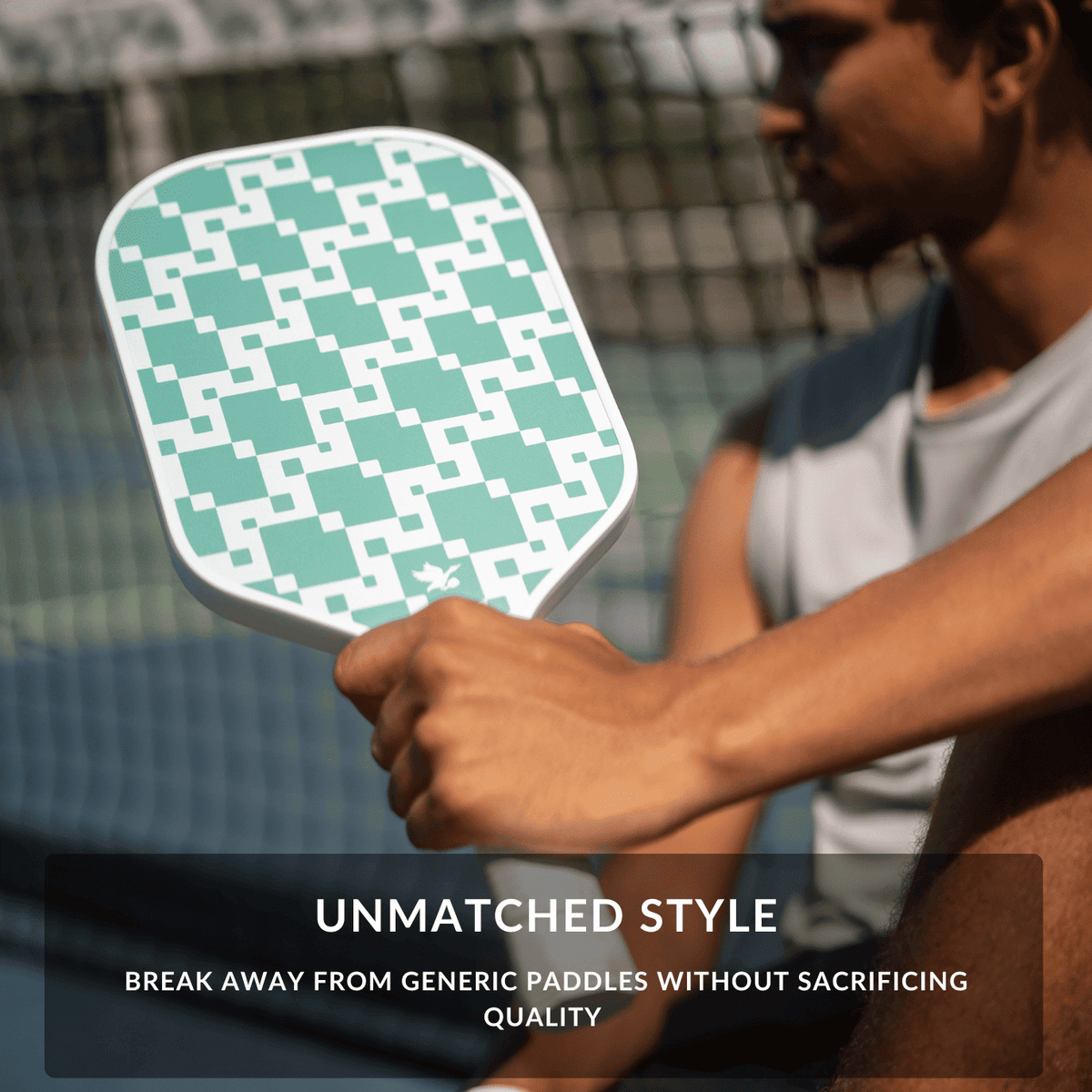 Person holding a paddle with a green knit geometric pattern, sitting on a pickleball court.