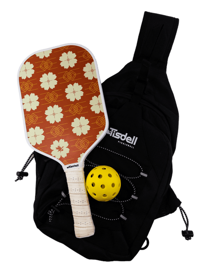 Floral-patterned pickleball paddle with a yellow ball and black bag on a transparent background