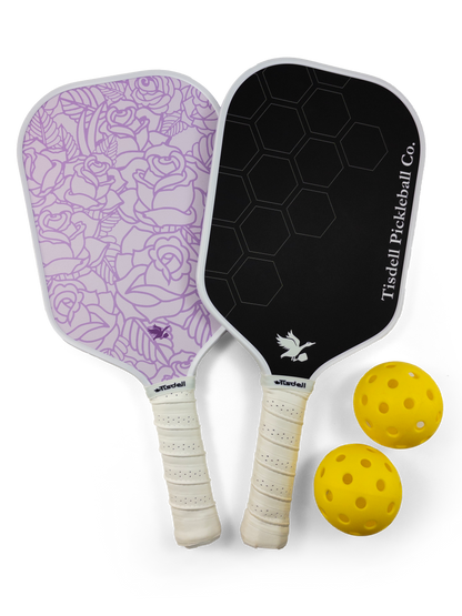 Two pickleball paddles with floral design and black surface, accompanied by two yellow balls on a white background.